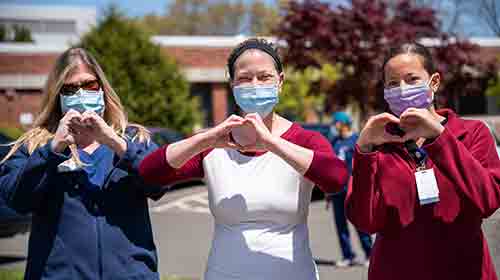 healthcare workers forming a heart with their hands