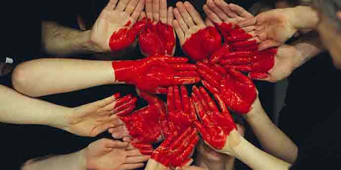 Crossed hands of multiple poeple with a red heart drawn
